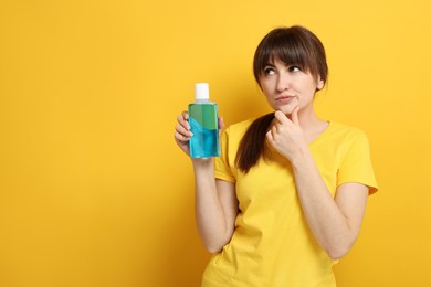 Photo of Young woman with mouthwash on yellow background, space for text
