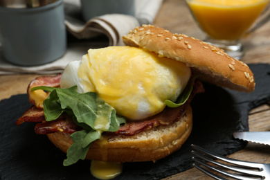 Photo of Delicious egg Benedict served on slate board, closeup