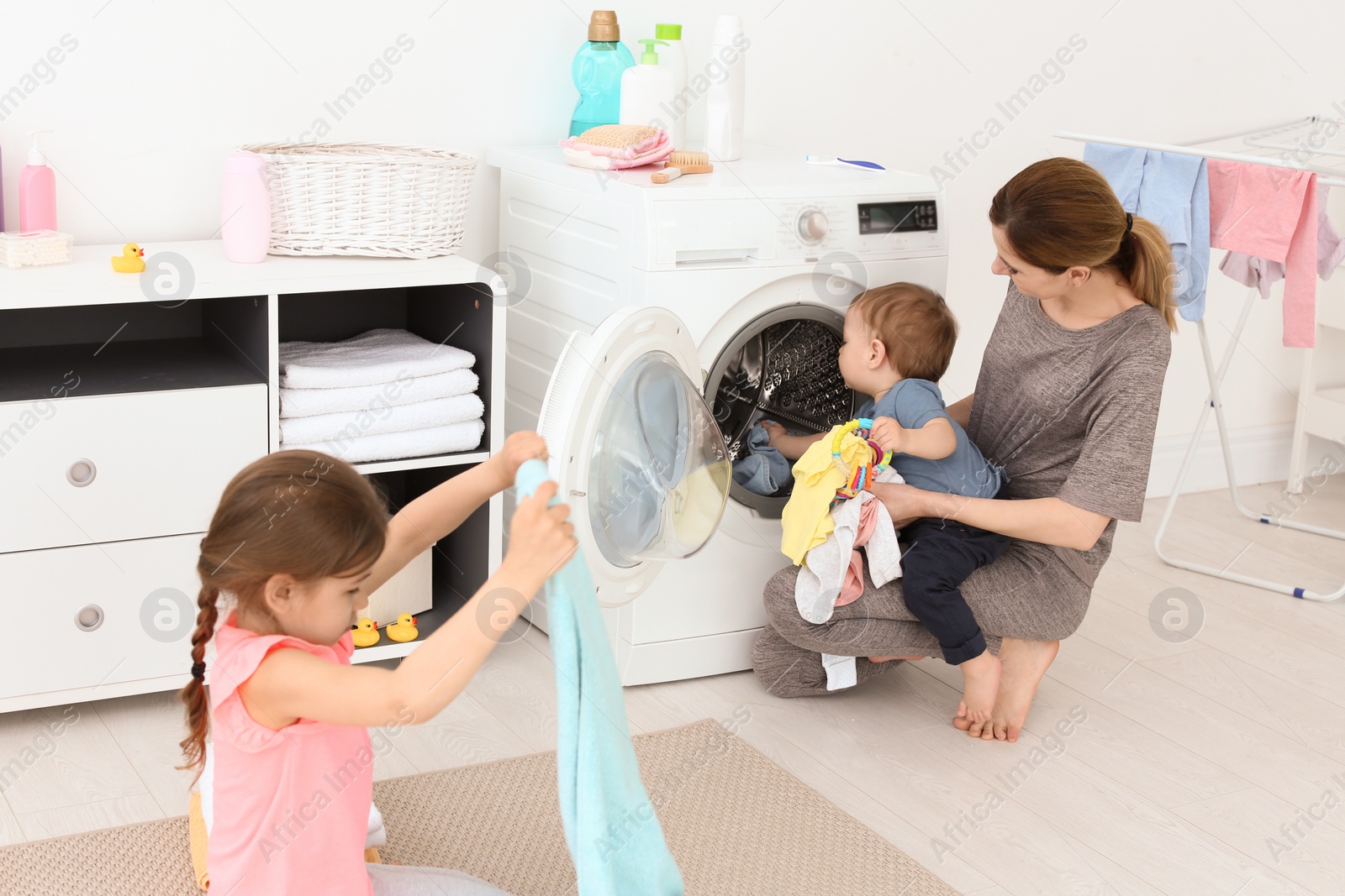 Photo of Housewife with little children doing laundry at home