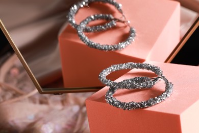 Elegant jewelry. Stylish presentation of luxury earrings on podium near mirror, closeup