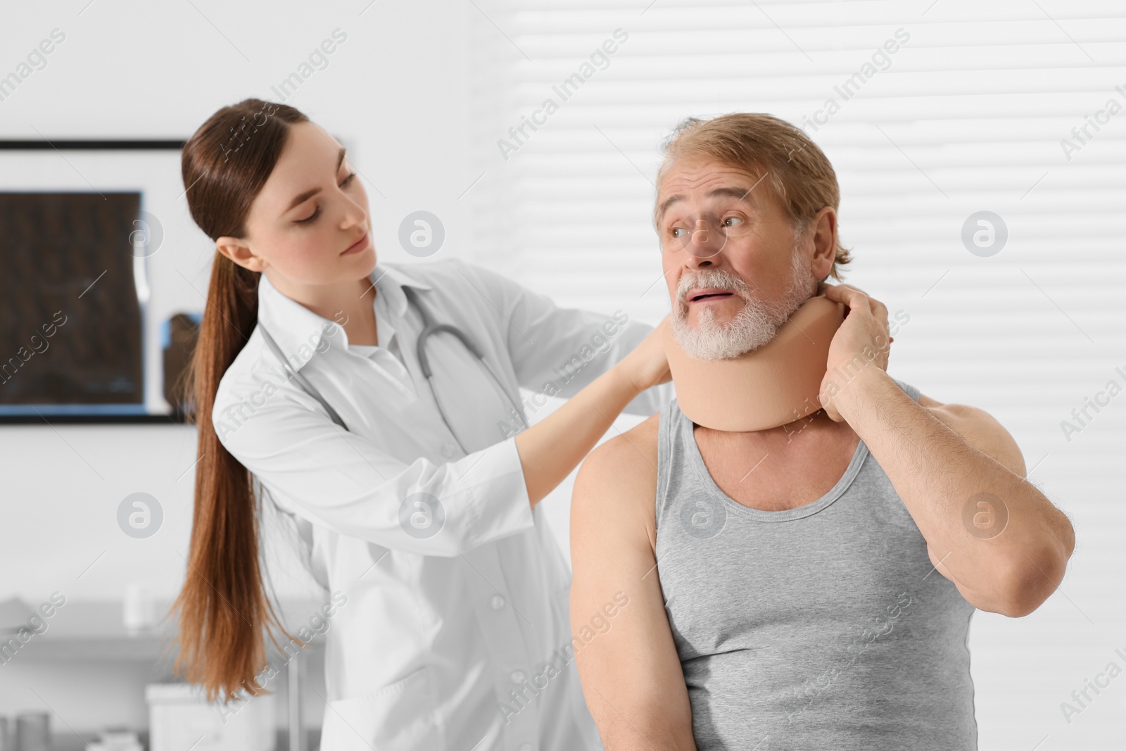 Photo of Orthopedist applying cervical collar onto patient's neck in clinic