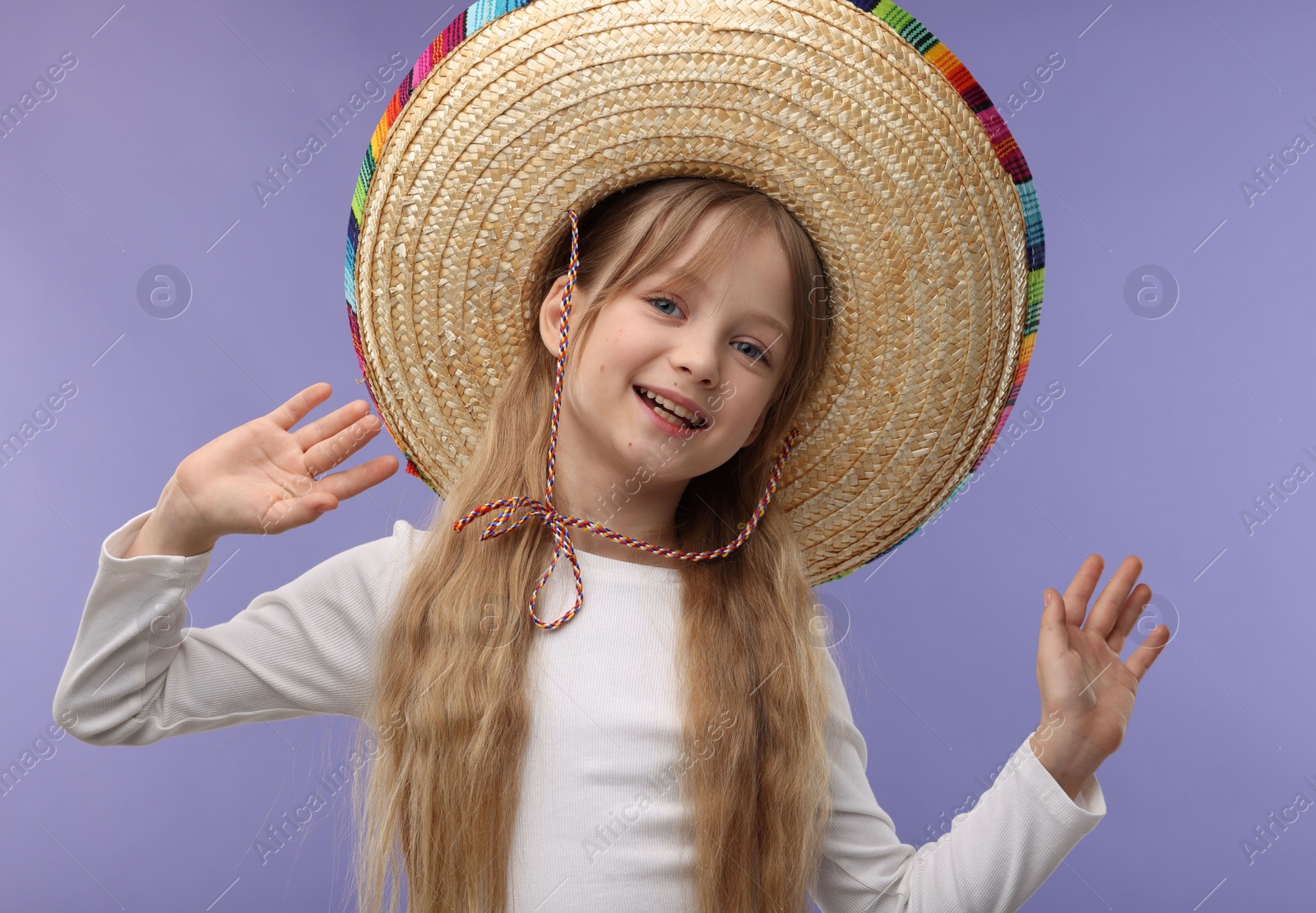 Photo of Cute girl in Mexican sombrero hat on purple background