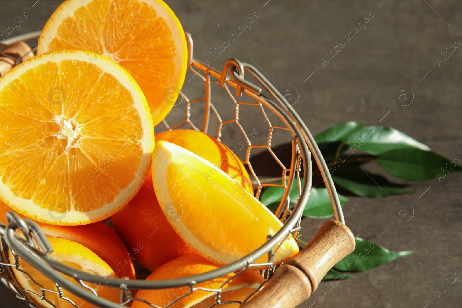 Photo of Fresh juicy oranges in basket on grey table, closeup