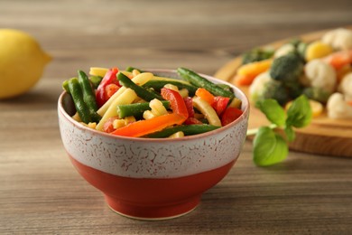 Photo of Frozen vegetables in bowl on wooden table, closeup