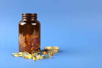 Jar with vitamin capsules on blue background, space for text