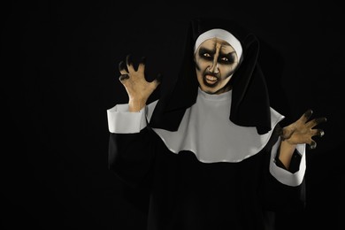 Photo of Scary devilish nun frightening on black background, space for text. Halloween party look