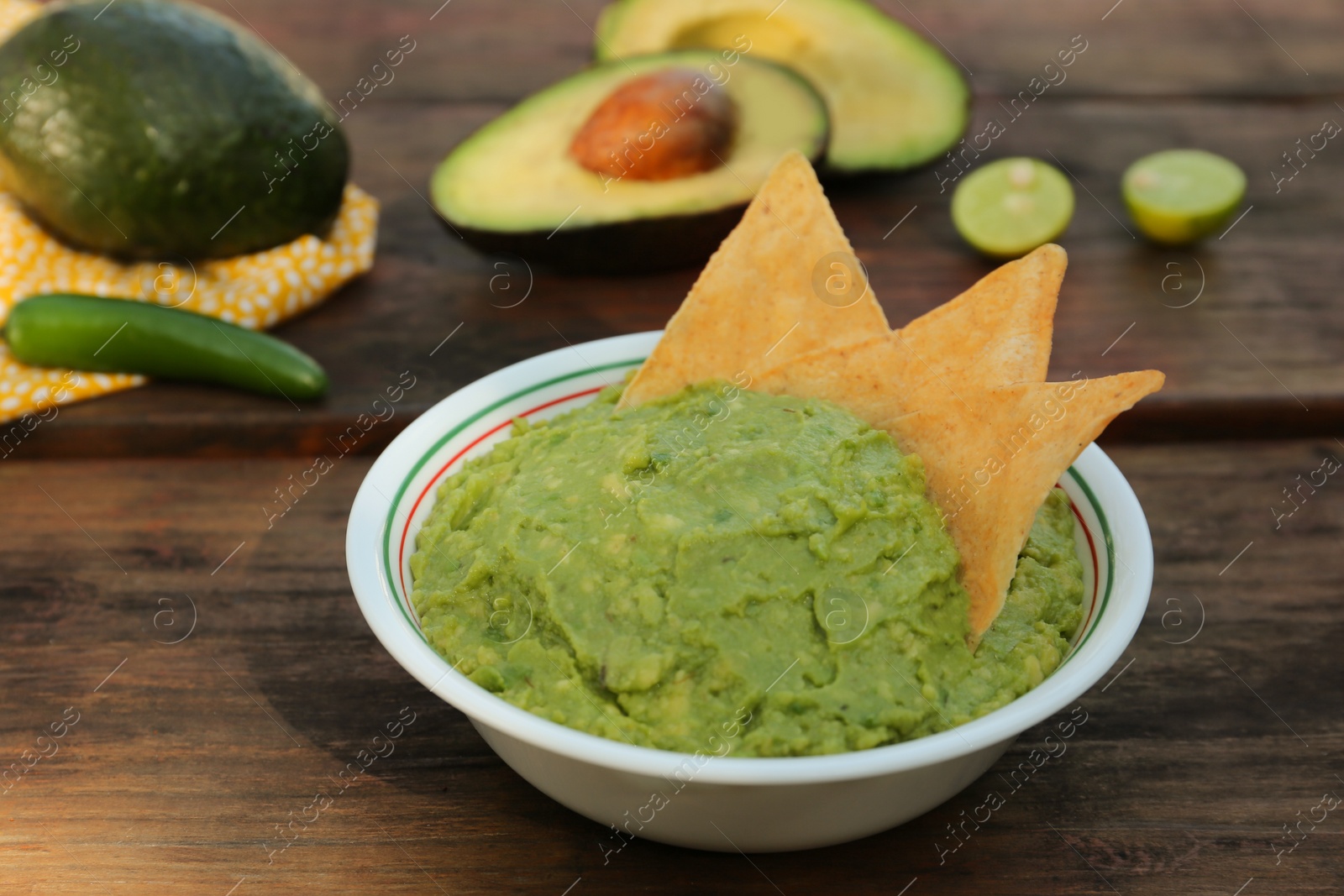 Photo of Delicious guacamole made of avocados with nachos on wooden table