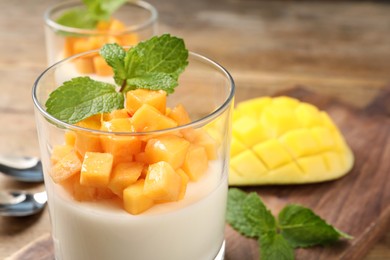 Photo of Delicious panna cotta with mango in glass dish on table, closeup