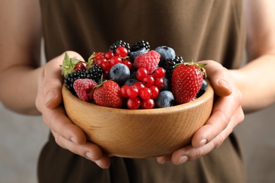 Photo of Woman with bowl of delicious summer berries, closeup