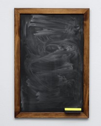 Dirty black chalkboard hanging on grey wall