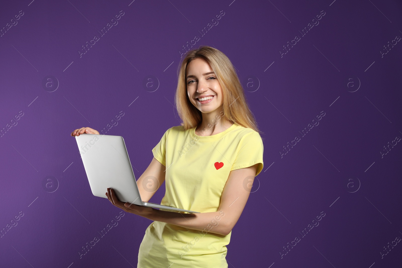 Photo of Portrait of young woman with modern laptop on purple background