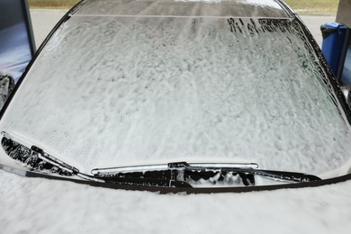 Photo of Auto with cleaning foam at car wash, closeup