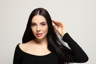 Portrait of beautiful young woman on light grey background