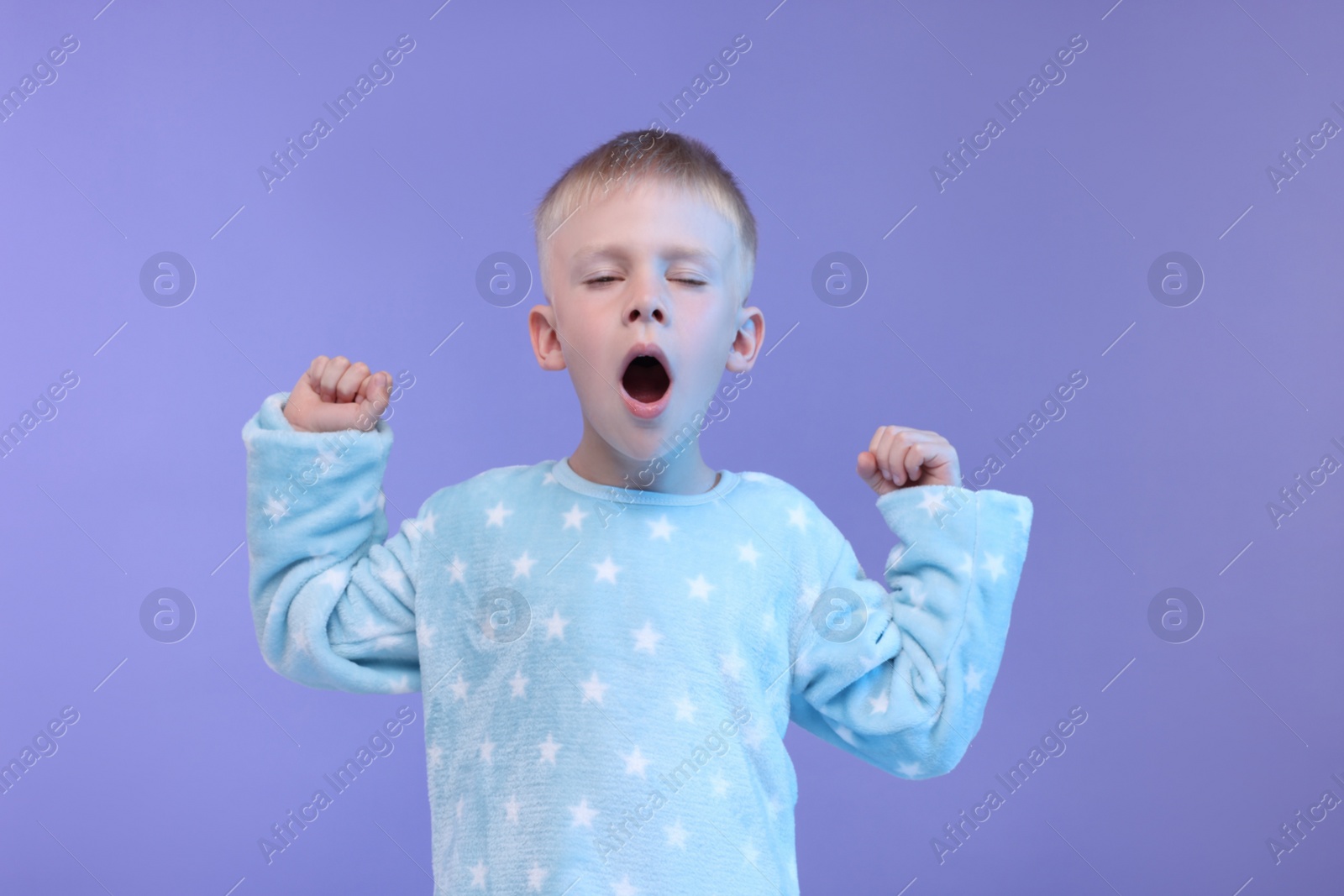 Photo of Sleepy boy yawning on purple background. Insomnia problem