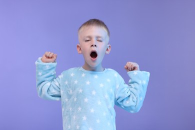 Sleepy boy yawning on purple background. Insomnia problem