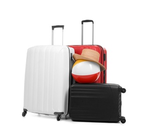 Photo of New suitcases with hat and inflatable ball packed for journey on white background