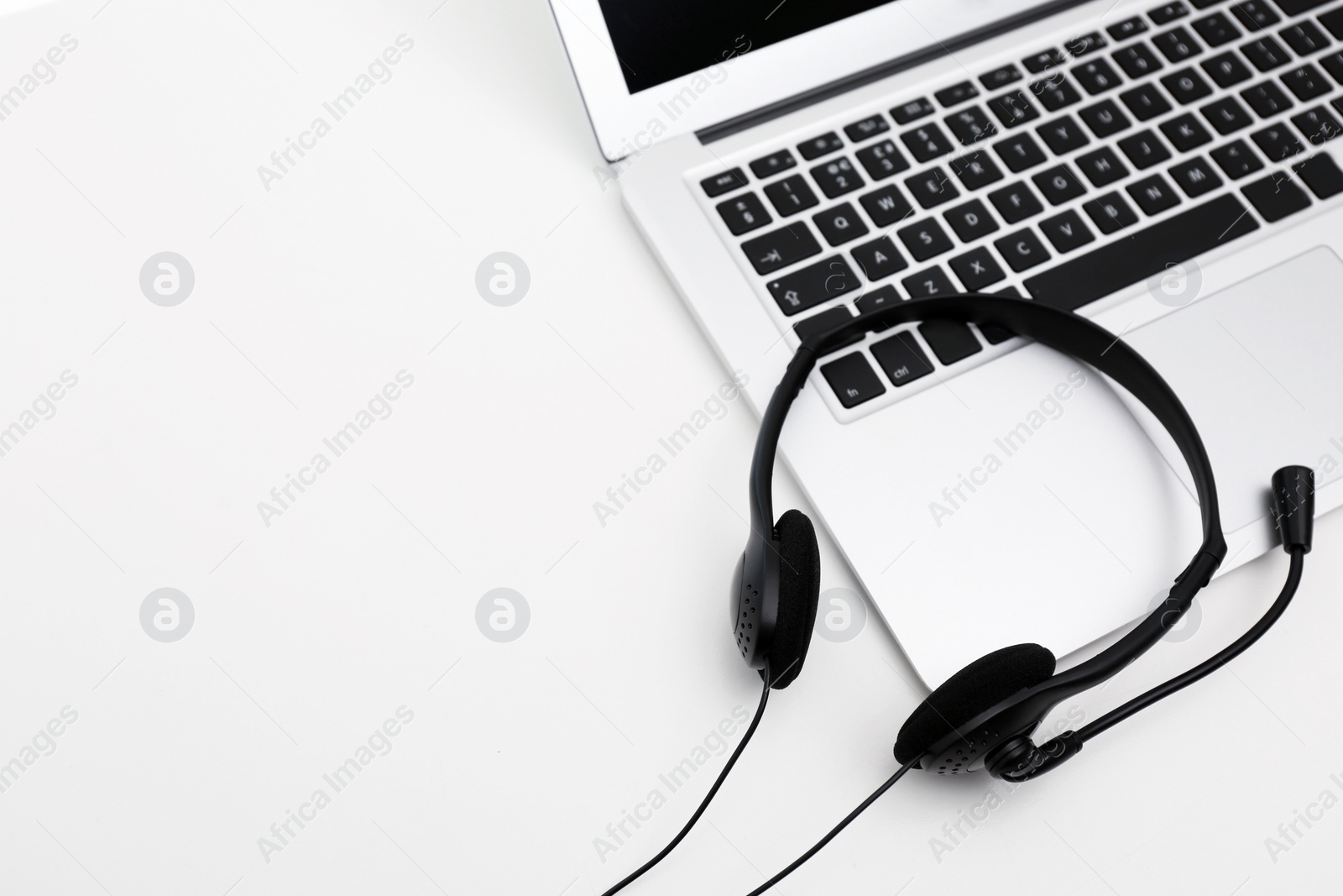 Photo of Modern laptop and headset on table, space for text. Technical support concept