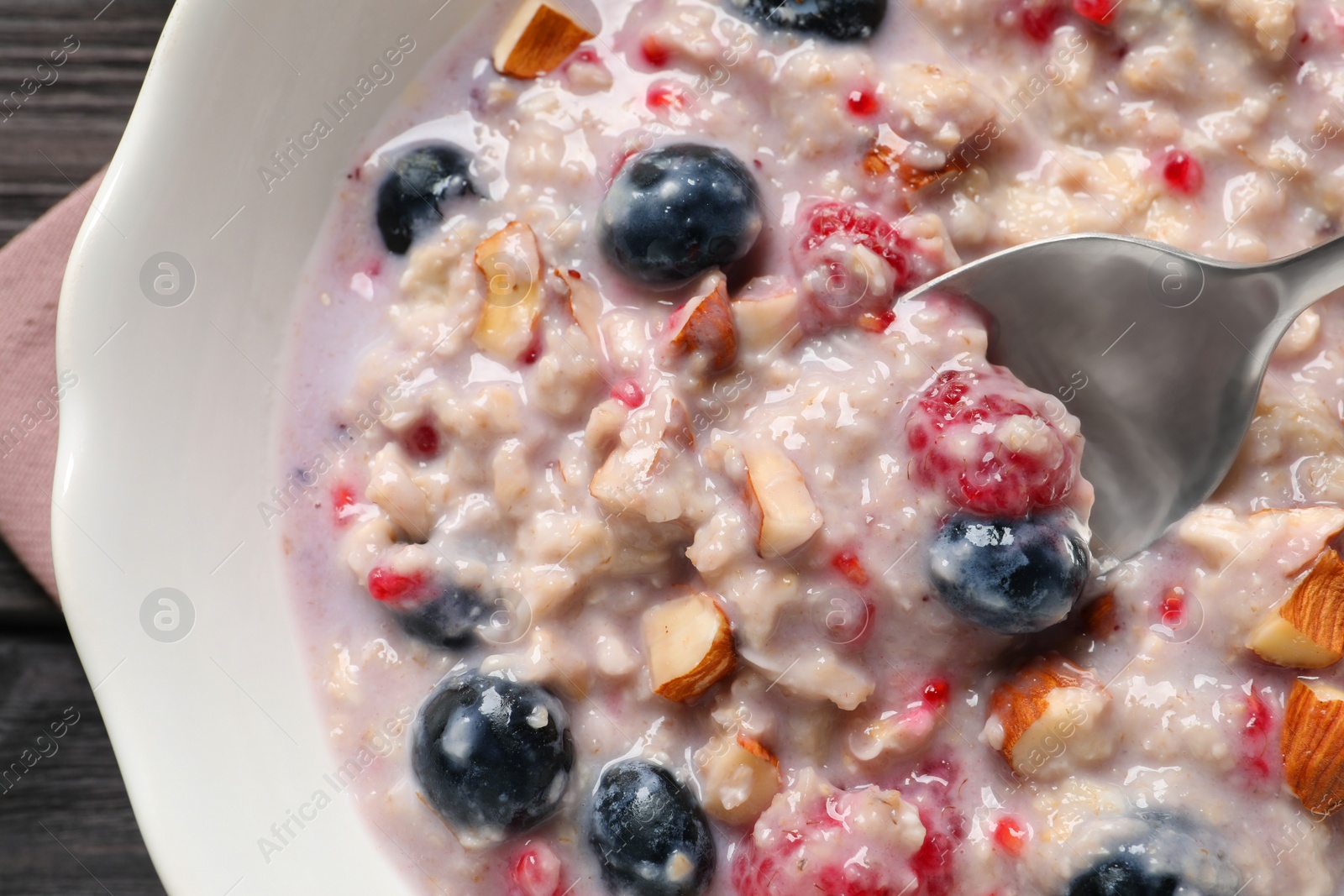 Photo of Tasty oatmeal porridge with toppings on wooden table, top view