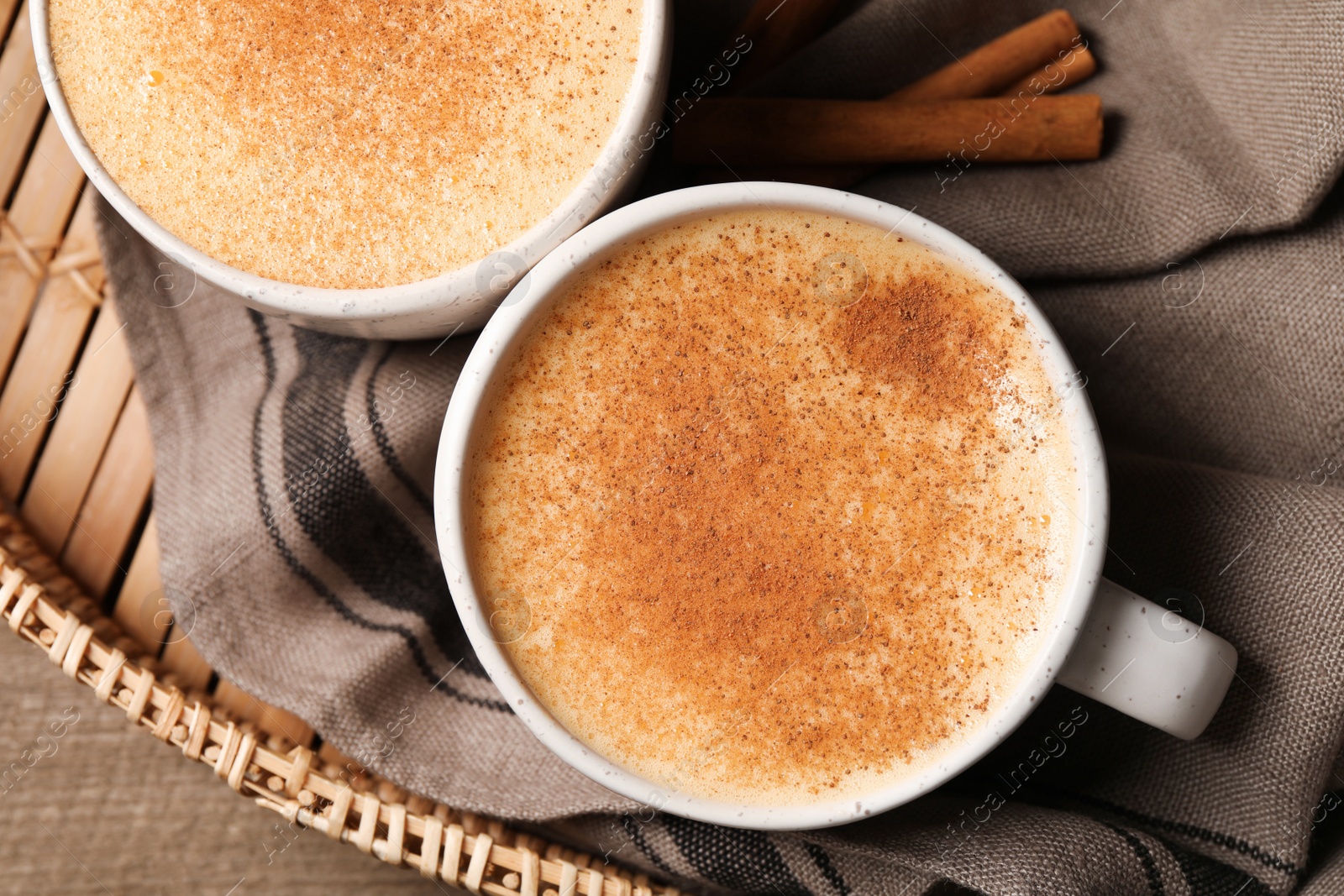 Photo of Delicious eggnog with cinnamon on wooden table, top view