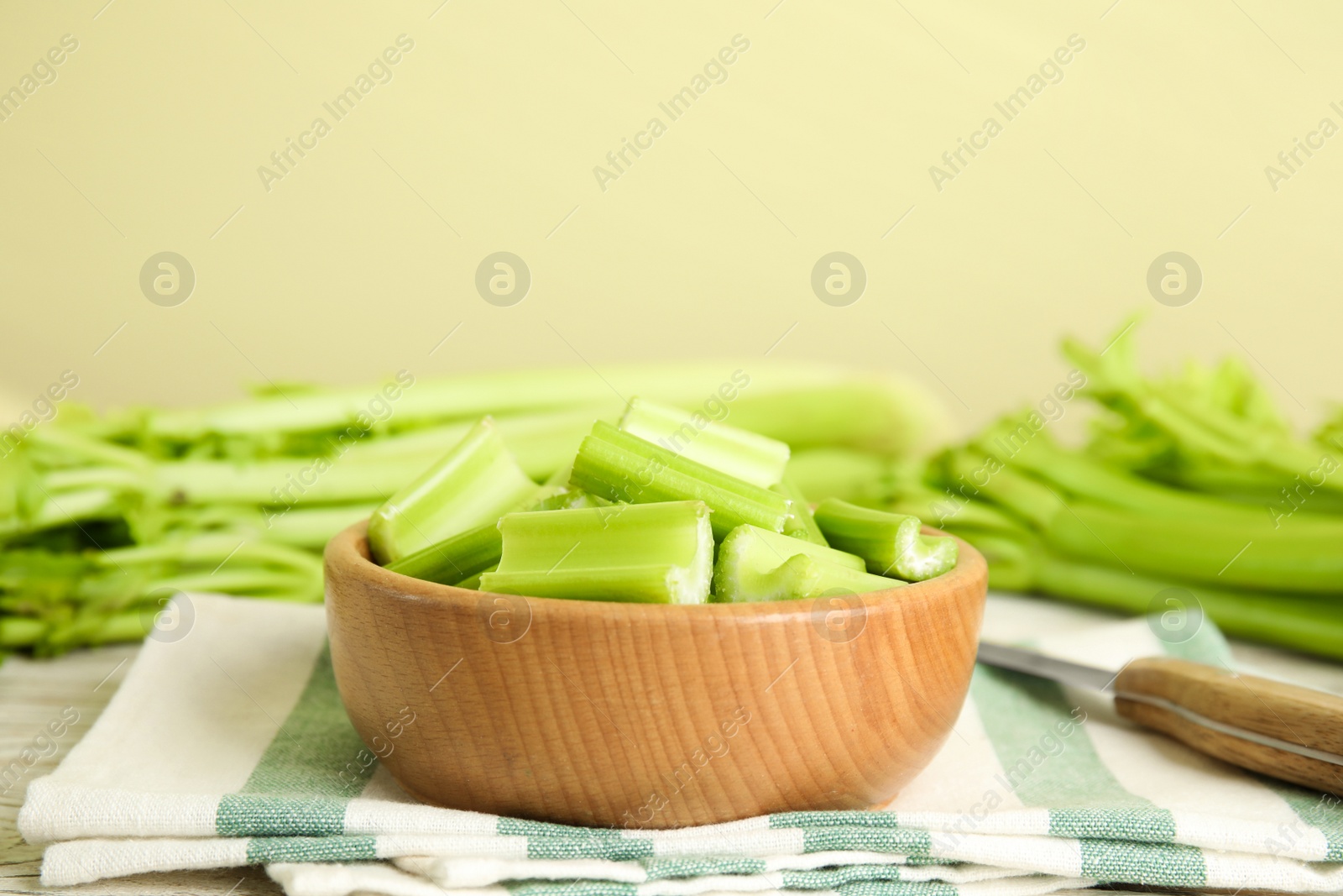 Photo of Cut celery in wooden bowl on table. Space for text