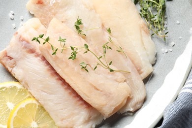 Photo of Raw cod fish, microgreens and lemon on plate, top view