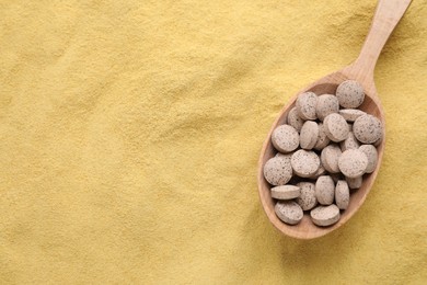 Photo of Wooden spoon of brewer`s yeast tablets on powder, top view