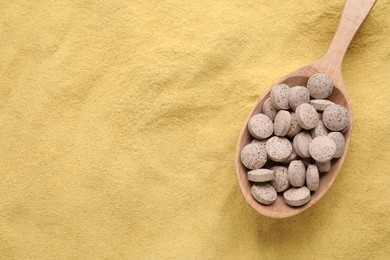 Wooden spoon of brewer`s yeast tablets on powder, top view