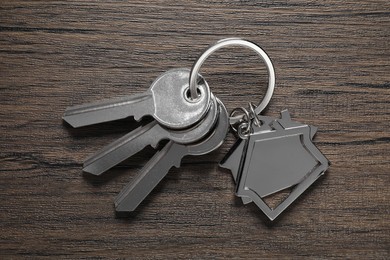 Photo of Keys with keychain in shapehouse on wooden table, top view