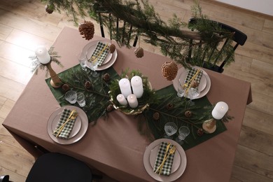 Christmas table setting with burning candles and other festive decor, above view