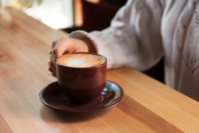 Photo of Woman with aromatic coffee at table in cafe, closeup