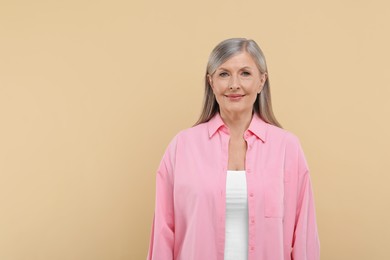 Photo of Portrait of beautiful senior woman on beige background. Space for text
