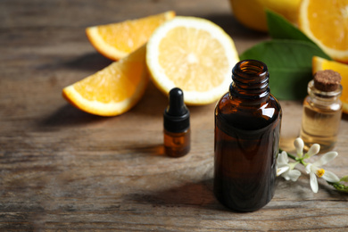 Photo of Bottles of citrus essential oil on wooden table. Space for text
