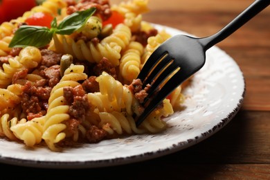 Photo of Plate of delicious pasta with minced meat and basil on wooden table, closeup