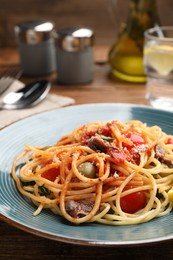 Delicious pasta with anchovies, tomatoes and parmesan cheese served on wooden table, closeup