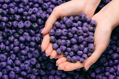Image of Woman holding heap of juicy fresh blueberries, top view
