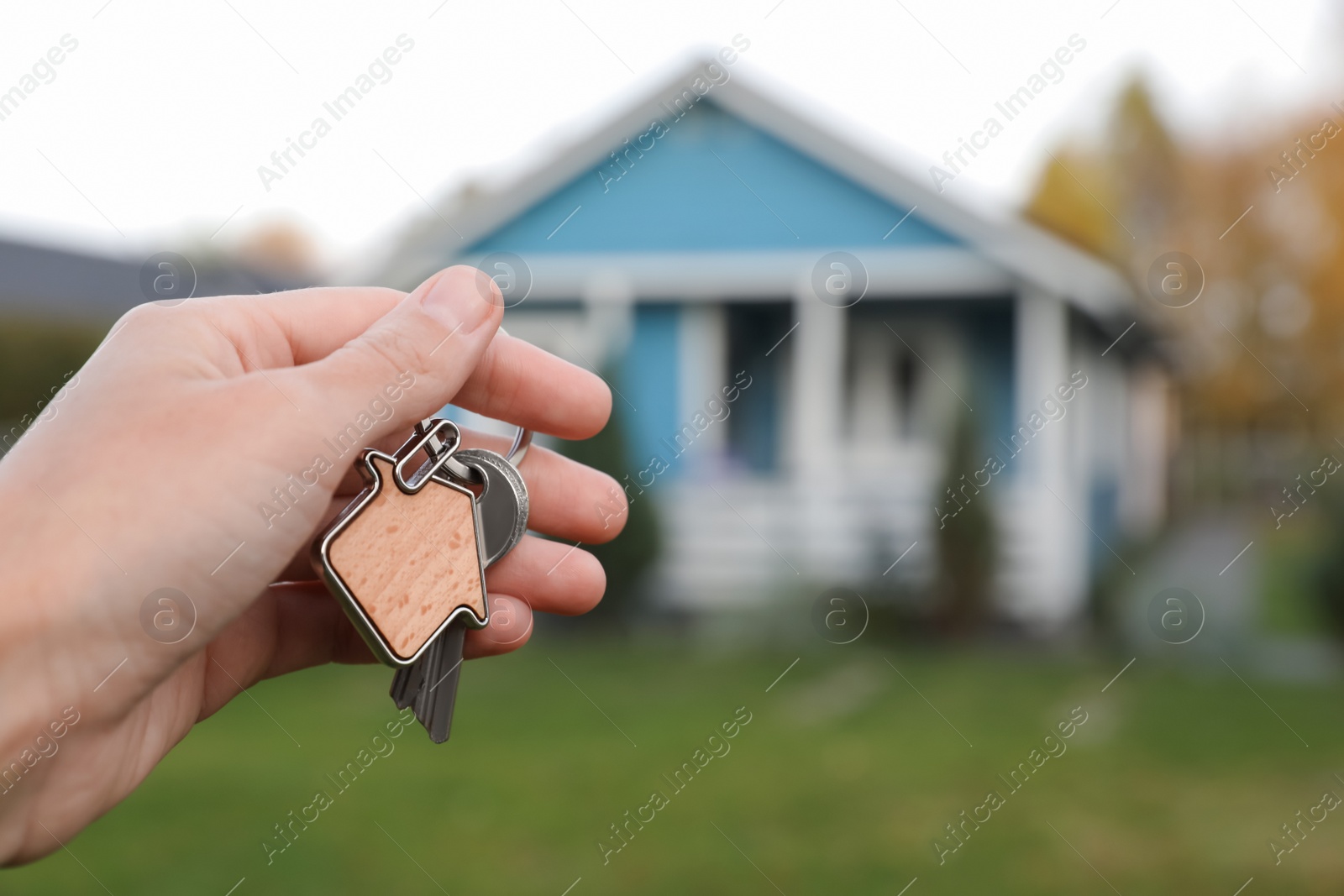 Photo of Woman holding house keys outdoors, closeup with space for text. Real estate agent