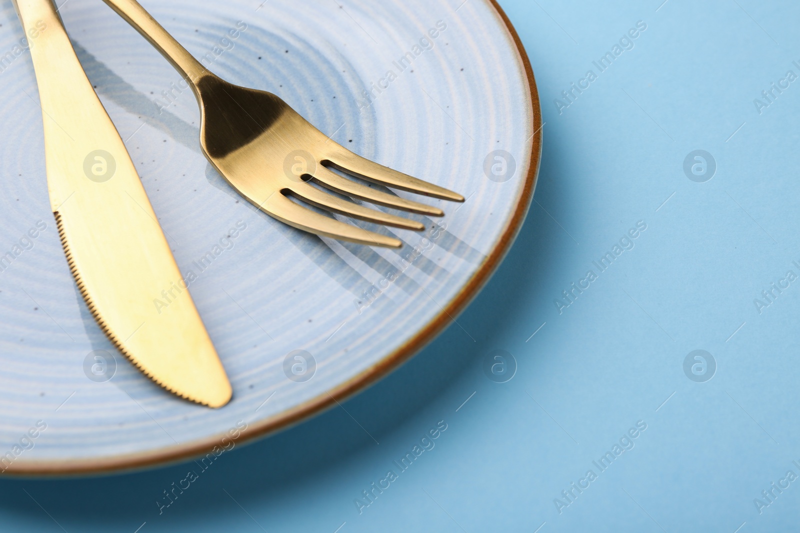 Photo of Setting with stylish cutlery on light blue table, closeup. Space for text