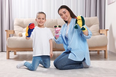 Happy mother and daughter playing with funny sock puppets together at home