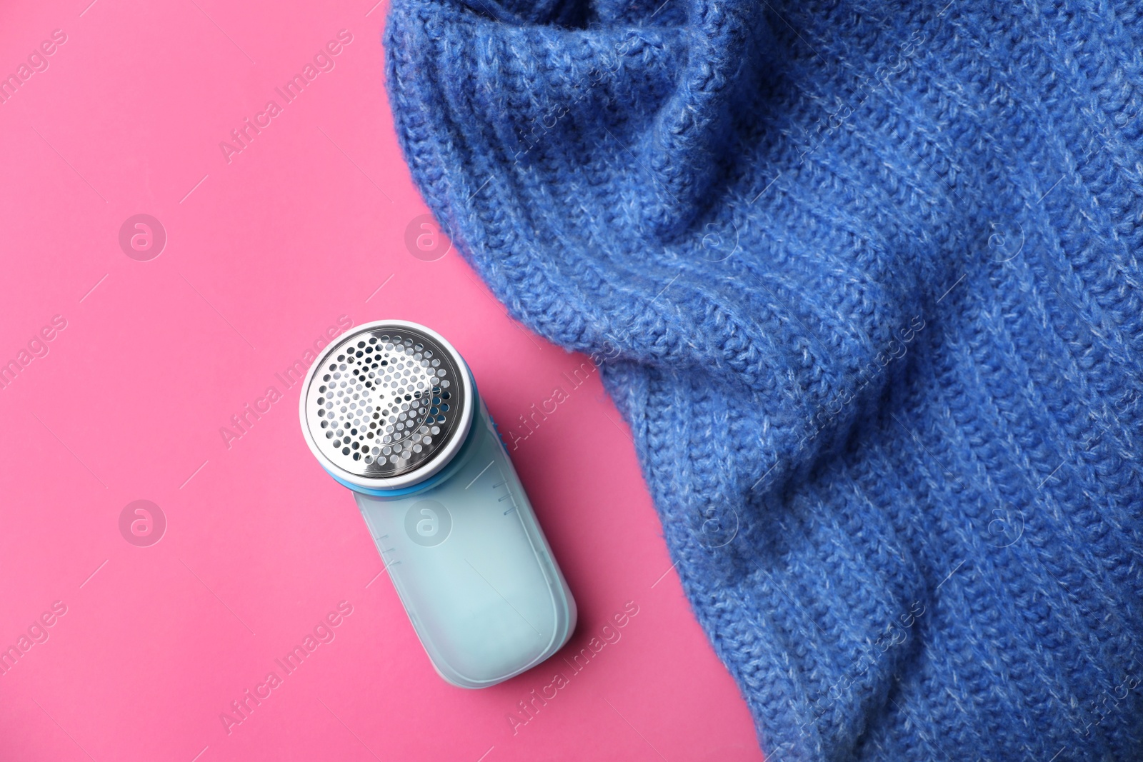 Photo of Modern fabric shaver and woolen sweater on pink background, flat lay