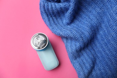 Modern fabric shaver and woolen sweater on pink background, flat lay