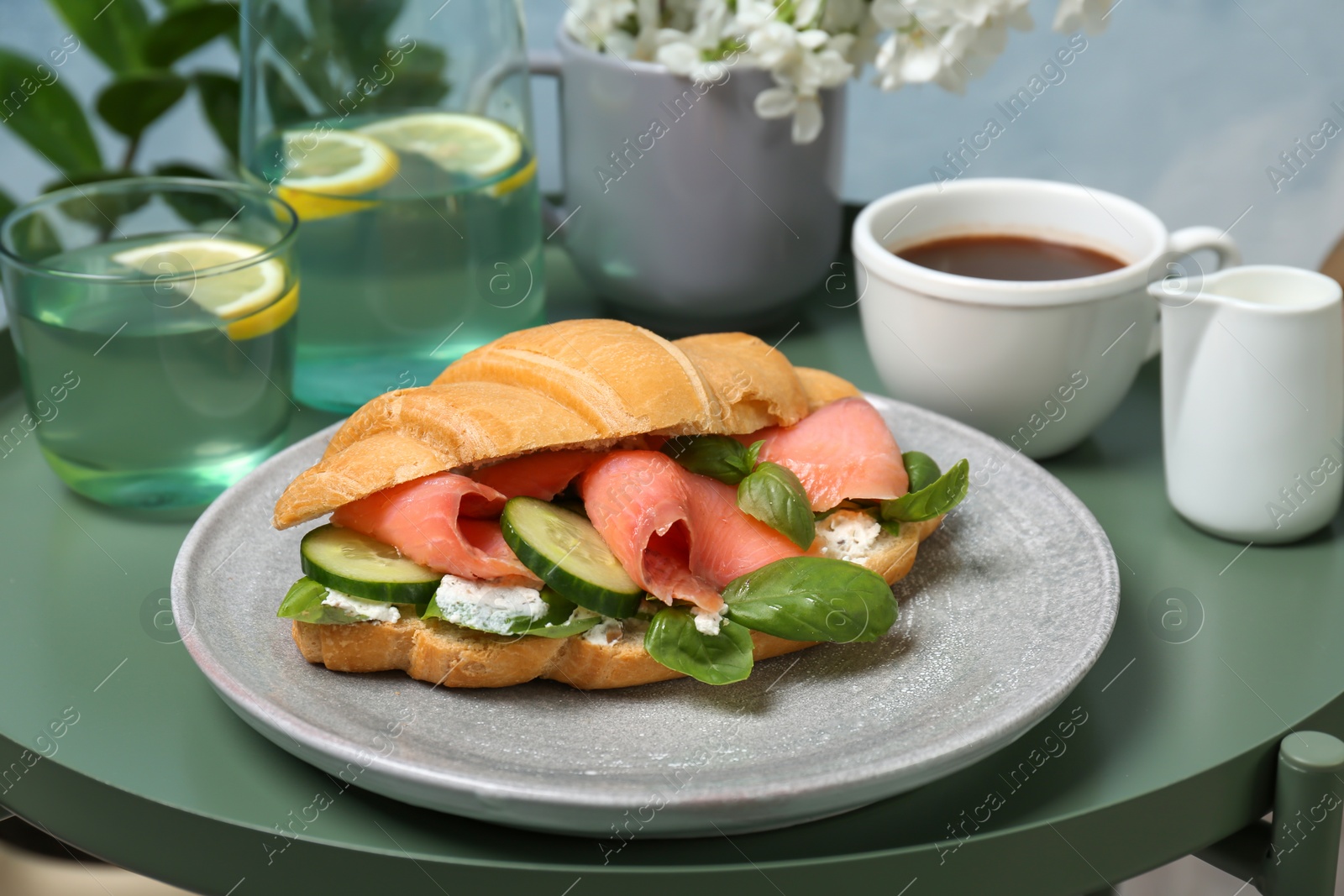 Photo of Plate with tasty croissant sandwich on table