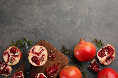 Photo of Delicious ripe pomegranates on grey table, flat lay. Space for text