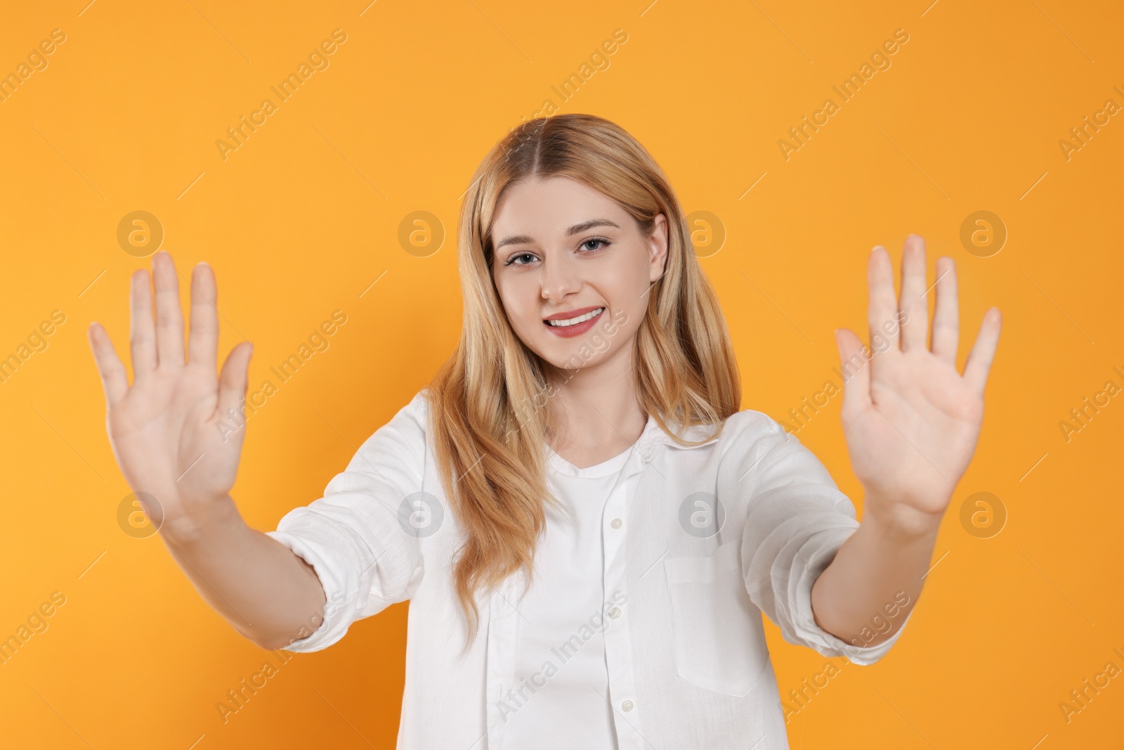 Photo of Happy woman giving high five with both hands on orange background