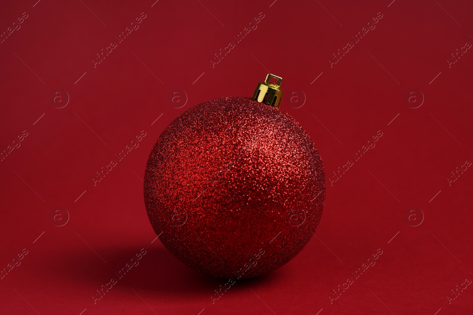 Photo of One glitter Christmas ball on red background