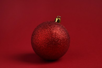 Photo of One glitter Christmas ball on red background
