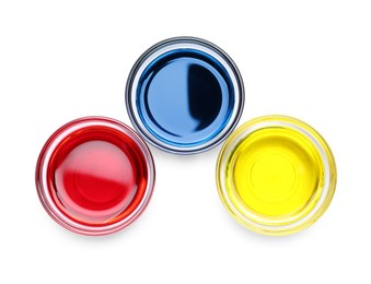Photo of Glass bowls with different food coloring on white background, top view
