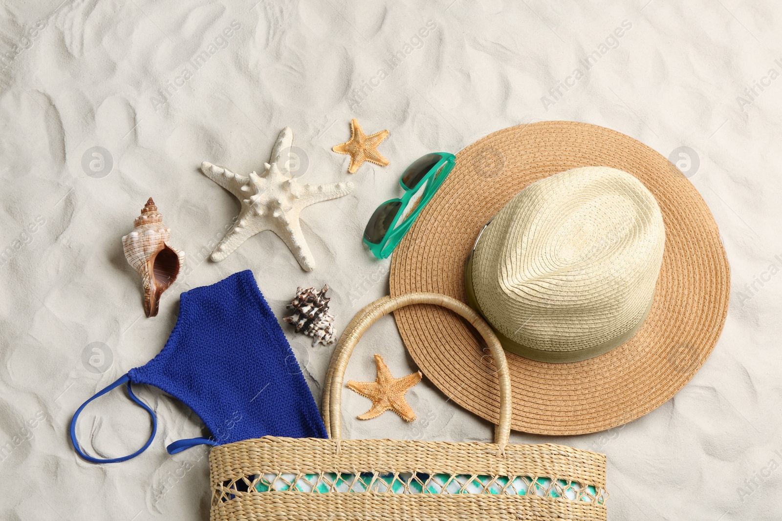 Photo of Different beach accessories on sand, flat lay