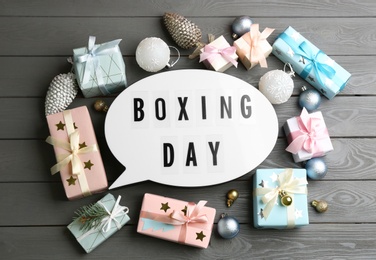 Flat lay composition with Boxing Day sign and Christmas gifts on grey wooden table