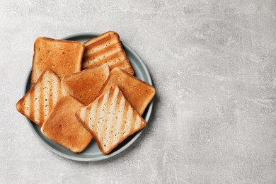 Photo of Slices of tasty toasted bread on light grey table, top view. Space for text
