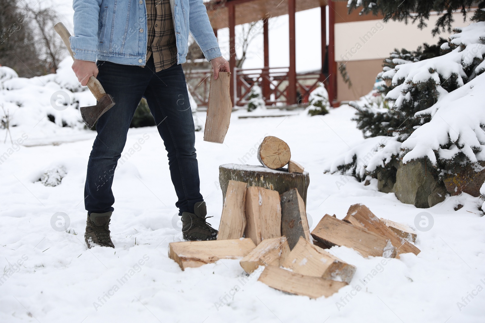 Photo of Man chopping wood with axe outdoors on winter day, closeup